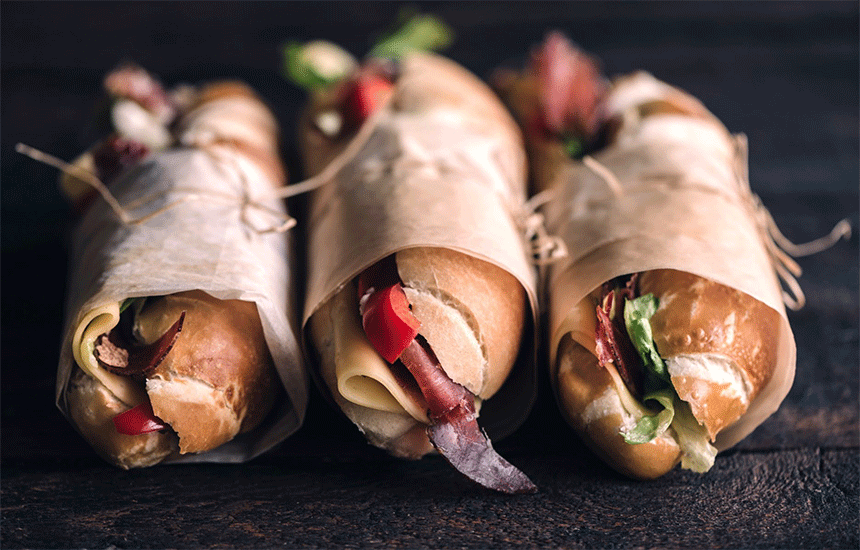Three sandwiches on a table.